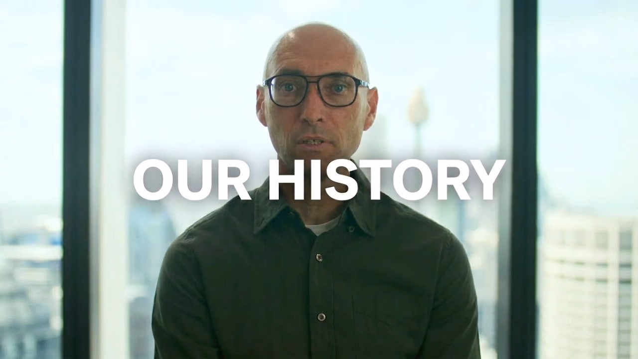 Michael Combs in front of a city skyline behind the title Our History.