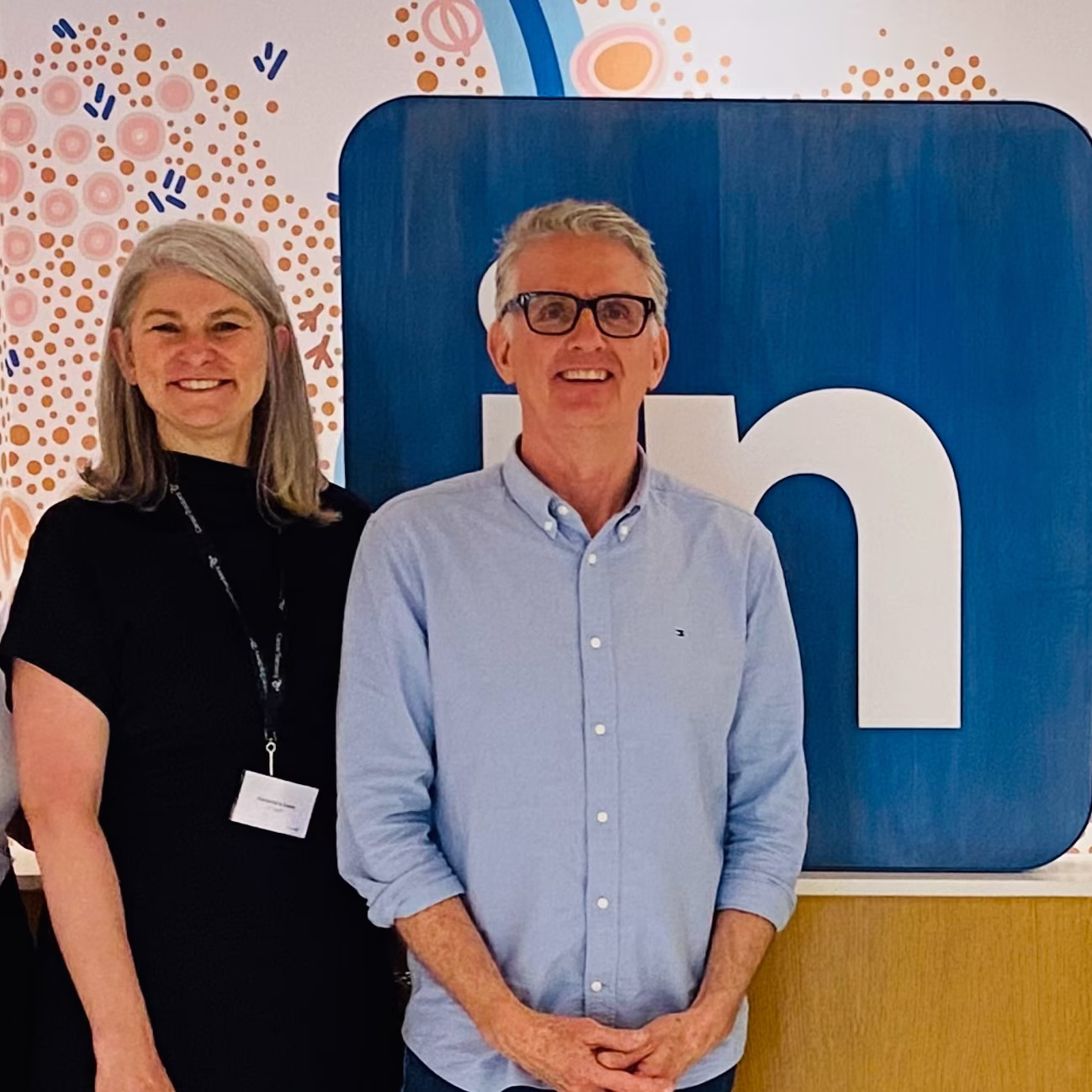 Matt Tindale and a LinkedIn colleague standing in front of a LinkedIn logo mural and a First Nations artwork.