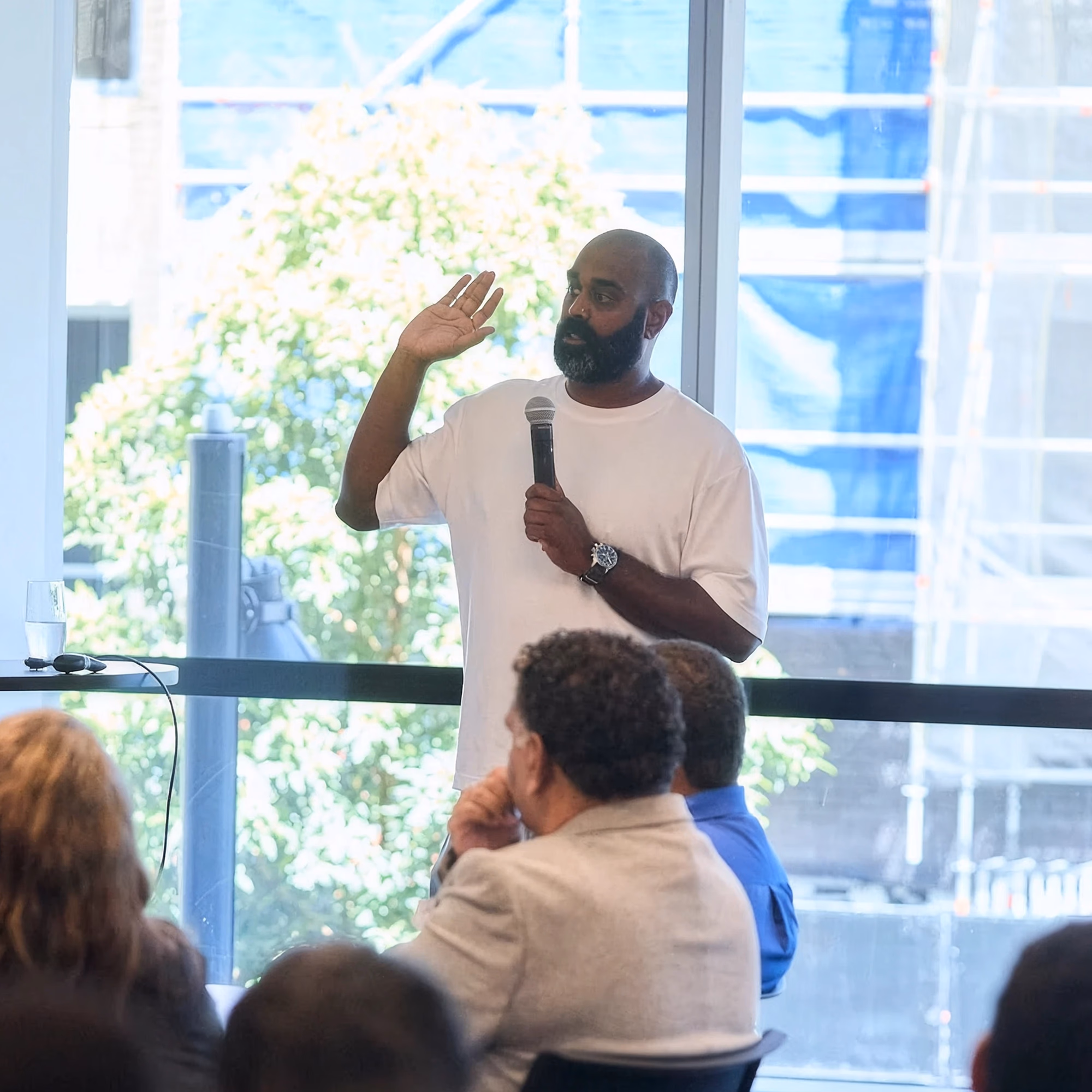 A speaker with a microphone addressing seated delegates at the CareerTrackers National Alumni Conference.