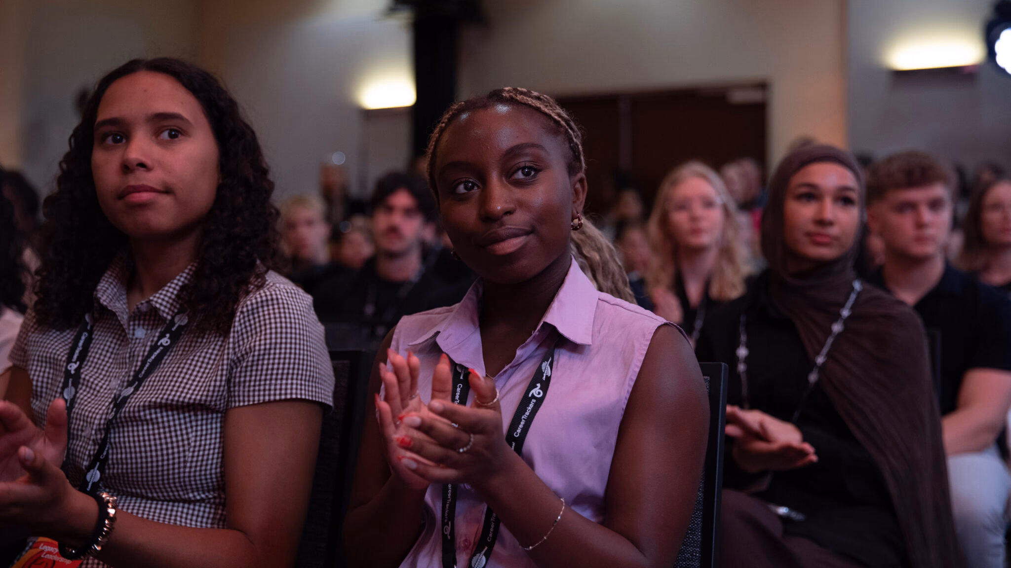 CareerTrackers interns applauding at a program event, wearing CareerTrackers lanyards.