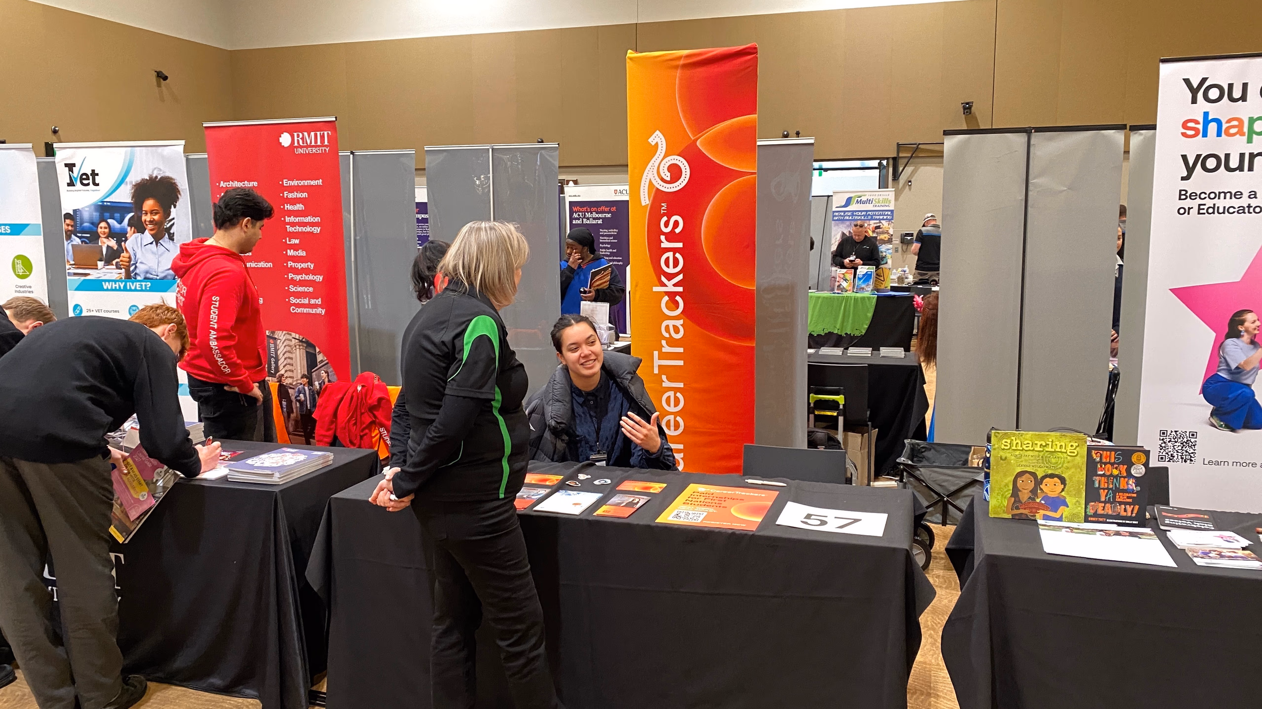 People talking at the CareerTrackers stall at a university careers fair, with the CareerTrackers banner behind the table.