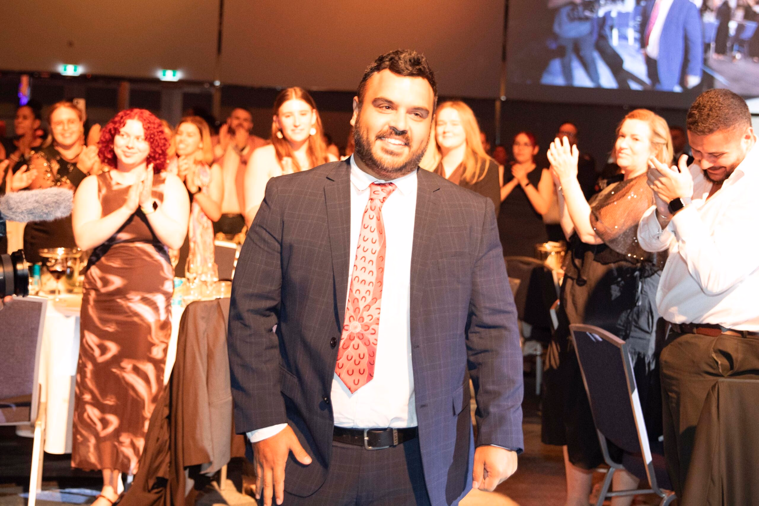 A CareerTrackers alumnus walking to the stage to applause at the CareerTrackers Gala Awards.